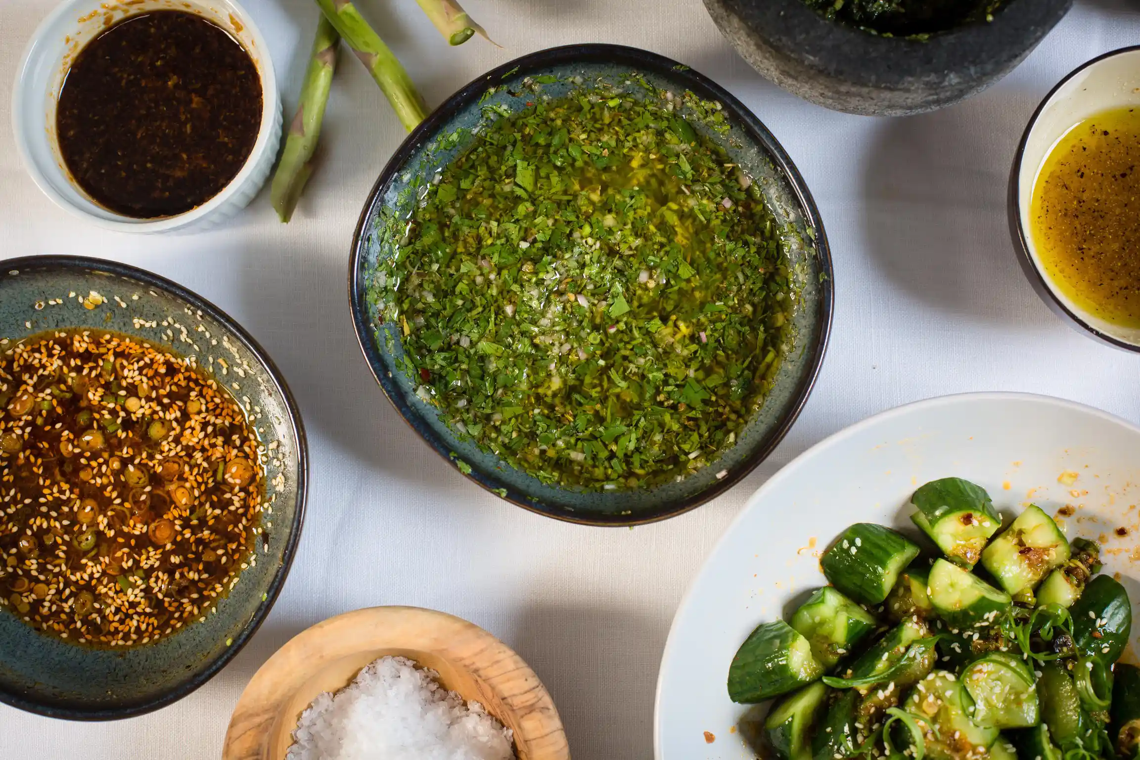 Herb sauces and sesame cucumber salad arranged on a table