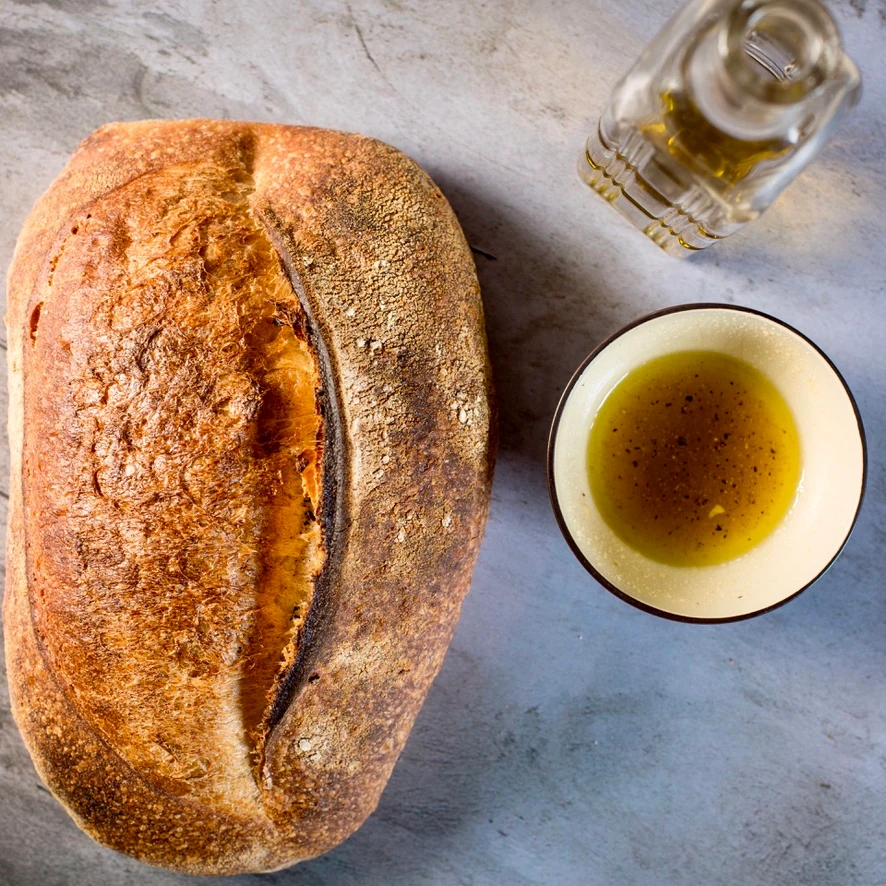Bread beside a bowl and bottle of olive oil